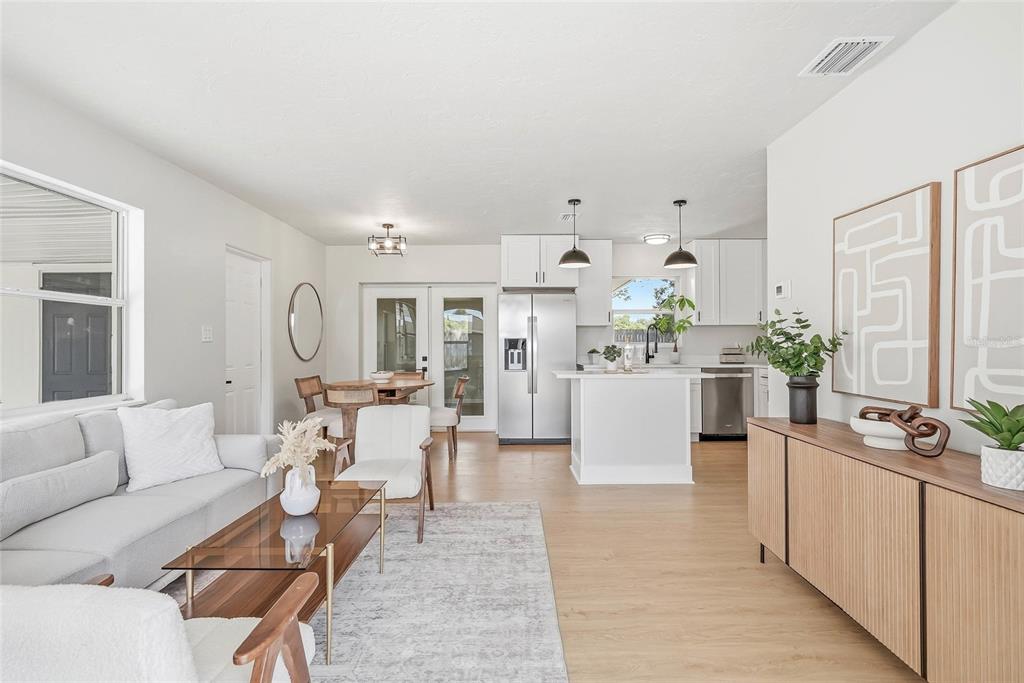 An open-concept living room and kitchen featuring light wood flooring and white cabinetry — 1306 DARTMOUTH DRIVE, BRADENTON, FL
