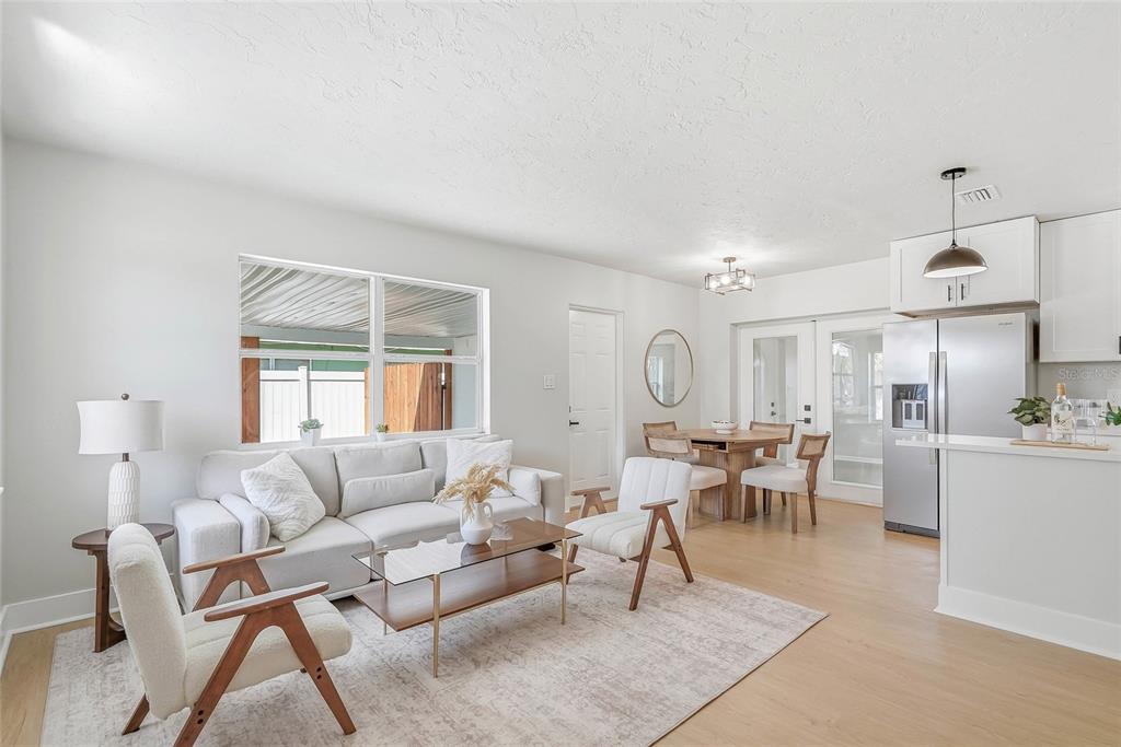 A bright living room and dining area feature light wood floors and white walls — 1306 DARTMOUTH DRIVE, BRADENTON, FL