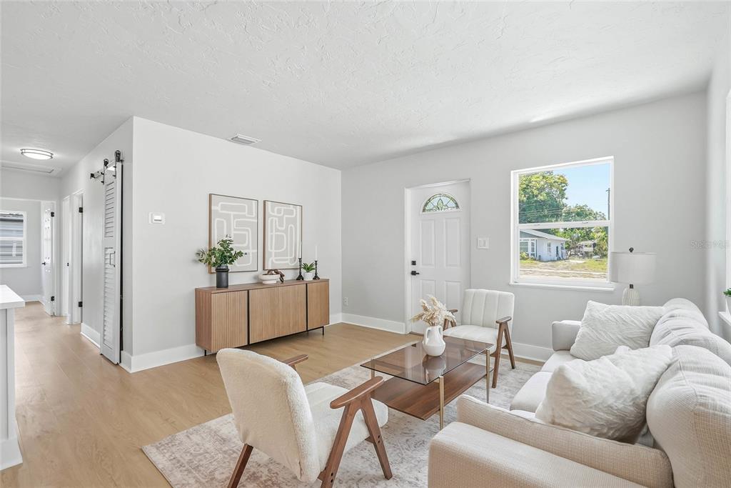 A bright living room features light wood flooring, a white sofa, and a wooden sideboard — 1306 DARTMOUTH DRIVE, BRADENTON, FL