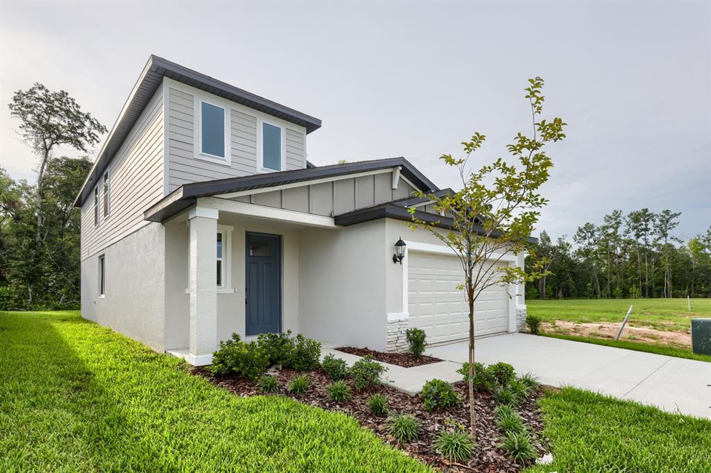 A two-story house with light-colored siding and stucco, a blue front door, and a garage — 7426 MIA VINE DRIVE, BROOKSVILLE, FL