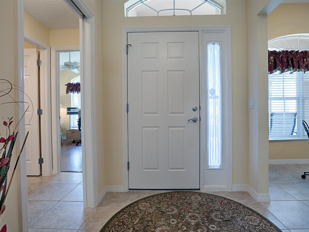 A foyer features a white front door, a side window, and tile flooring — 1979 REMBERT ROAD, THE VILLAGES, FL