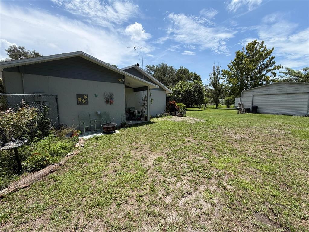 A view of a house exterior with a grassy backyard and a detached metal garage — 3707 36TH STREET E, BRADENTON, FL