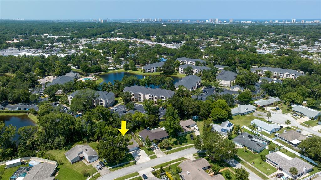 An aerial view shows a residential neighborhood with a yellow arrow pointing to a house — 909 BENTWOOD LANE UNIT 1, PORT ORANGE, FL
