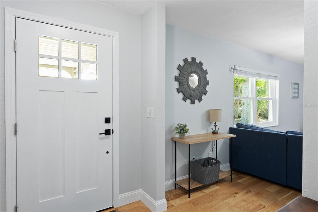 An entryway features a white front door, a console table, and a blue sofa nearby — 909 BENTWOOD LANE UNIT 1, PORT ORANGE, FL