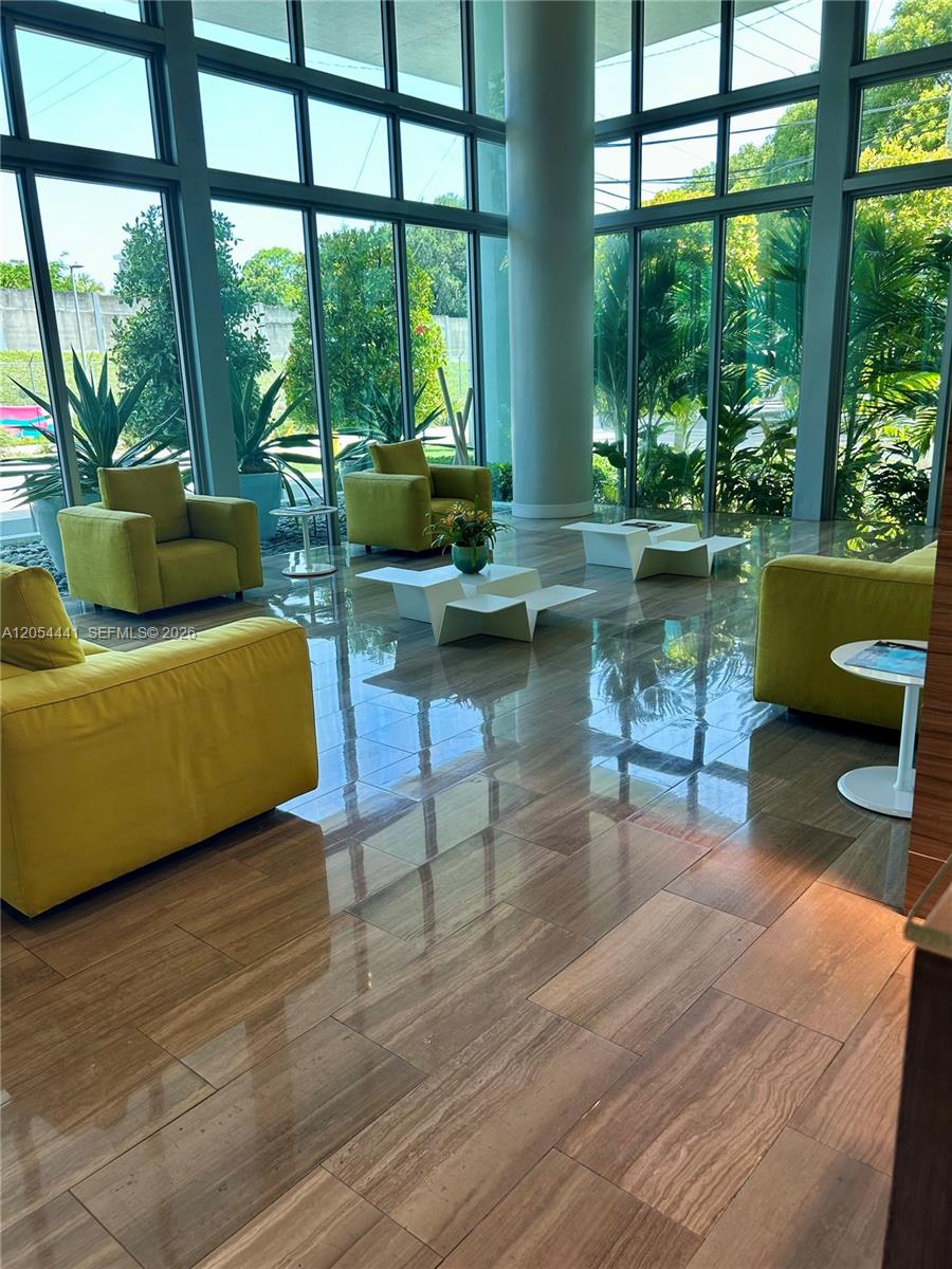 A modern lobby features floor-to-ceiling windows, lime green armchairs, and polished wood-look tile flooring — 1600 SW 1st Ave # 812, Miami FL 33129, MIAMI, FL