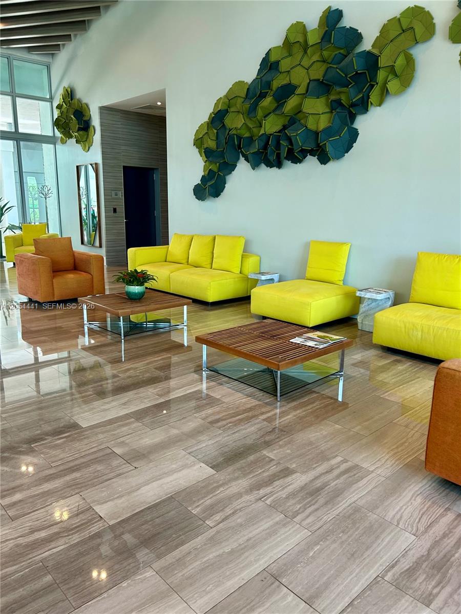 A modern lobby features yellow and orange seating, a slatted coffee table, and wall art — 1600 SW 1st Ave # 812, Miami FL 33129, MIAMI, FL