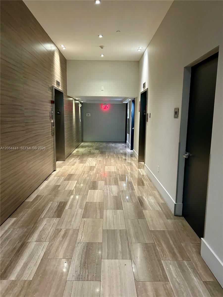 A hallway features wood-paneled walls, tile flooring, and two elevator doors — 1600 SW 1st Ave # 812, Miami FL 33129, MIAMI, FL