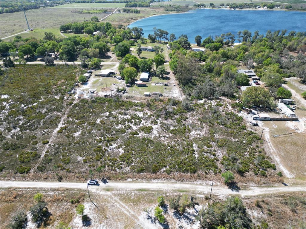 An aerial view shows a large, undeveloped sandy lot with scattered vegetation near a lake — HAMMERMILL AVENUE, LAKE WALES, FL