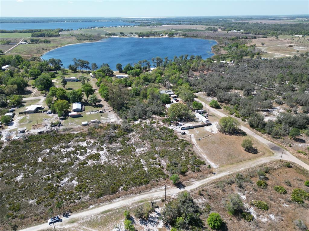 An aerial view shows a lake surrounded by trees, rural land, and scattered residential structures — HAMMERMILL AVENUE, LAKE WALES, FL