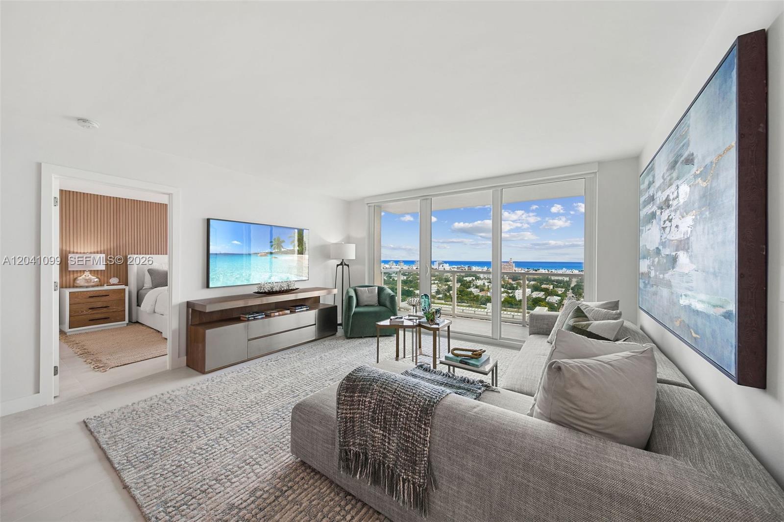 A modern living room features a large sectional sofa, media console, and floor-to-ceiling balcony windows — 650 West Ave # 1908, Miami Beach FL 33139, MIAMI BEACH, FL