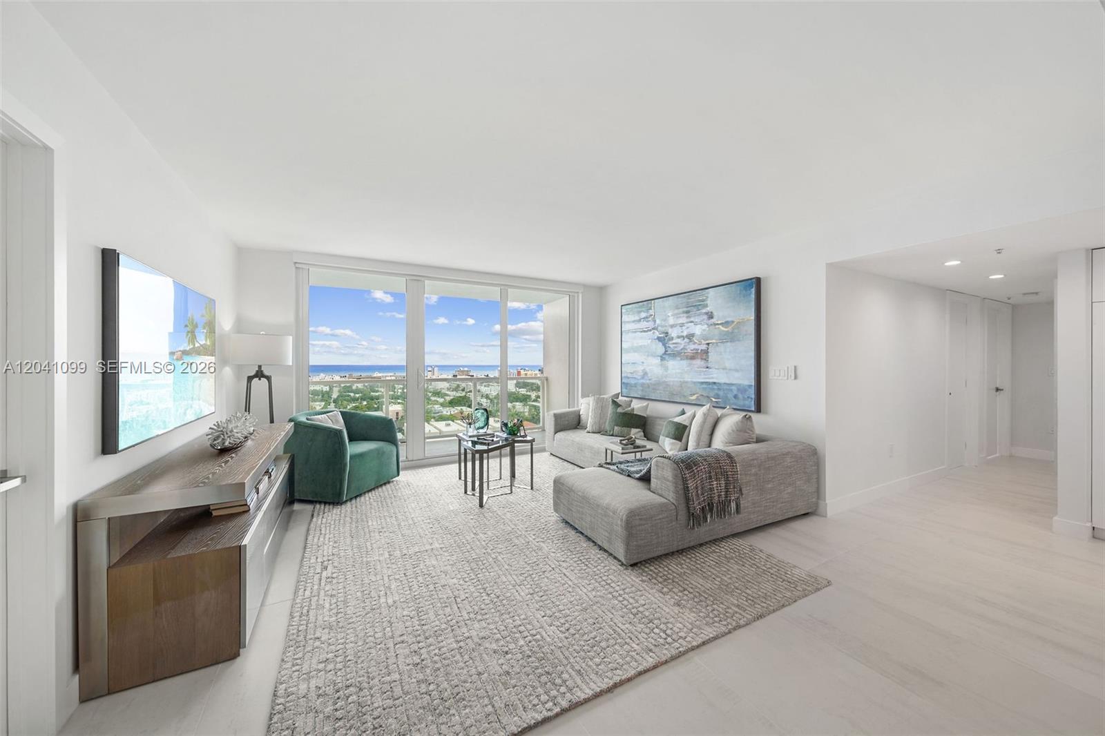 A modern living room features a gray sectional sofa, green armchair, and floor-to-ceiling windows — 650 West Ave # 1908, Miami Beach FL 33139, MIAMI BEACH, FL