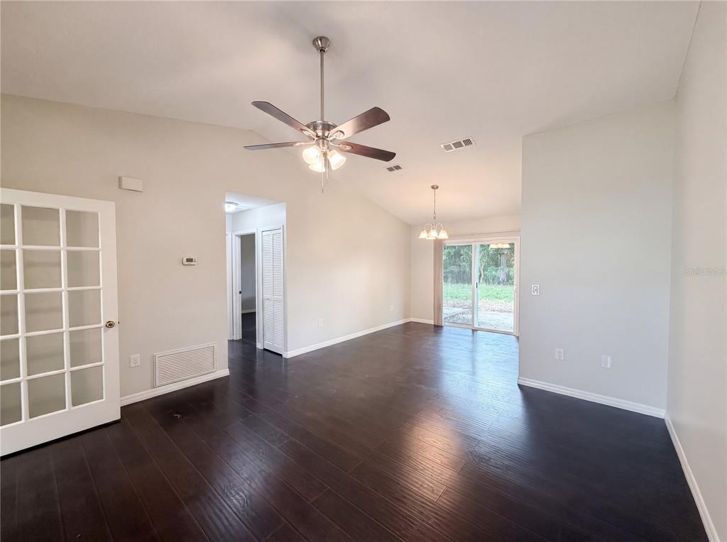 A living room with dark wood flooring, a vaulted ceiling, a ceiling fan, and sliding doors — 3622 SHADY GROVE CIRCLE, ORLANDO, FL
