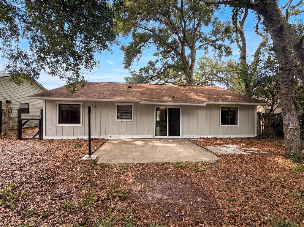 The exterior of a single-story house features light-colored vertical siding, a concrete patio, and trees — 3622 SHADY GROVE CIRCLE, ORLANDO, FL