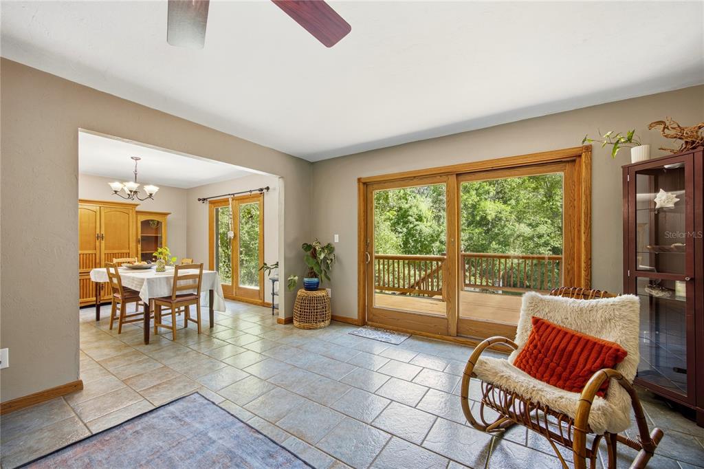 A dining area and living space with tile floors, sliding glass doors, and a rocking chair — 3519 NW 30TH BOULEVARD, GAINESVILLE, FL