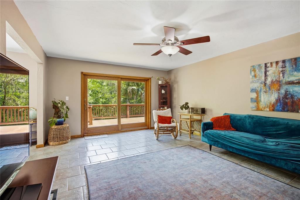 A living room features tile flooring, a teal sofa, a ceiling fan, and sliding glass doors — 3519 NW 30TH BOULEVARD, GAINESVILLE, FL