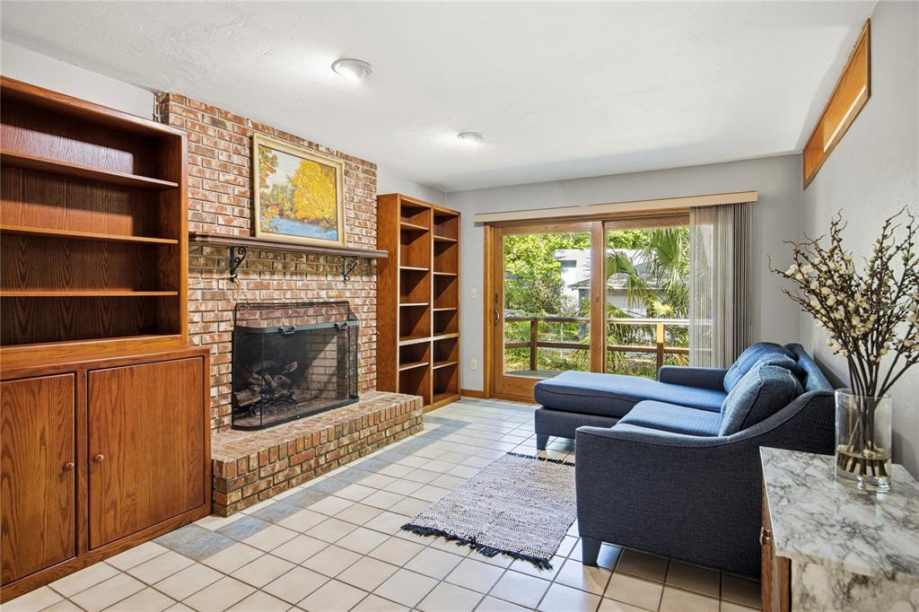 A living room features a brick fireplace, built-in wooden bookshelves, tile flooring, and a sliding door — 3519 NW 30TH BOULEVARD, GAINESVILLE, FL