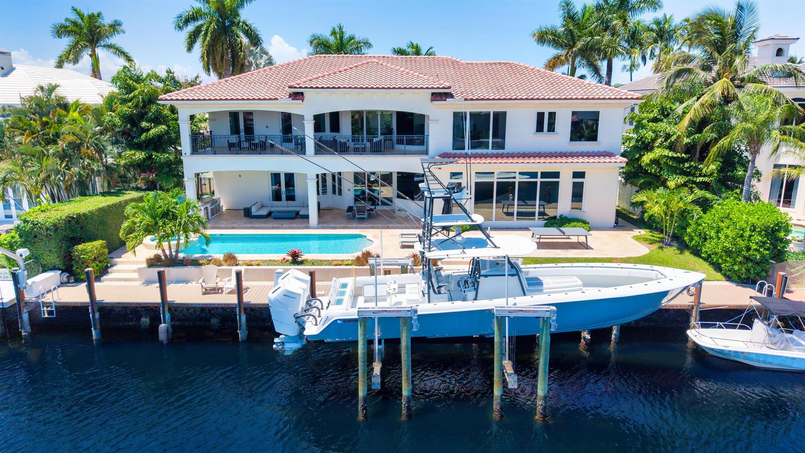 An aerial view of a two-story waterfront home with a swimming pool and a boat lift — 2320 NE 34th Court, Lighthouse Point FL 33064, LIGHTHOUSE POINT, FL
