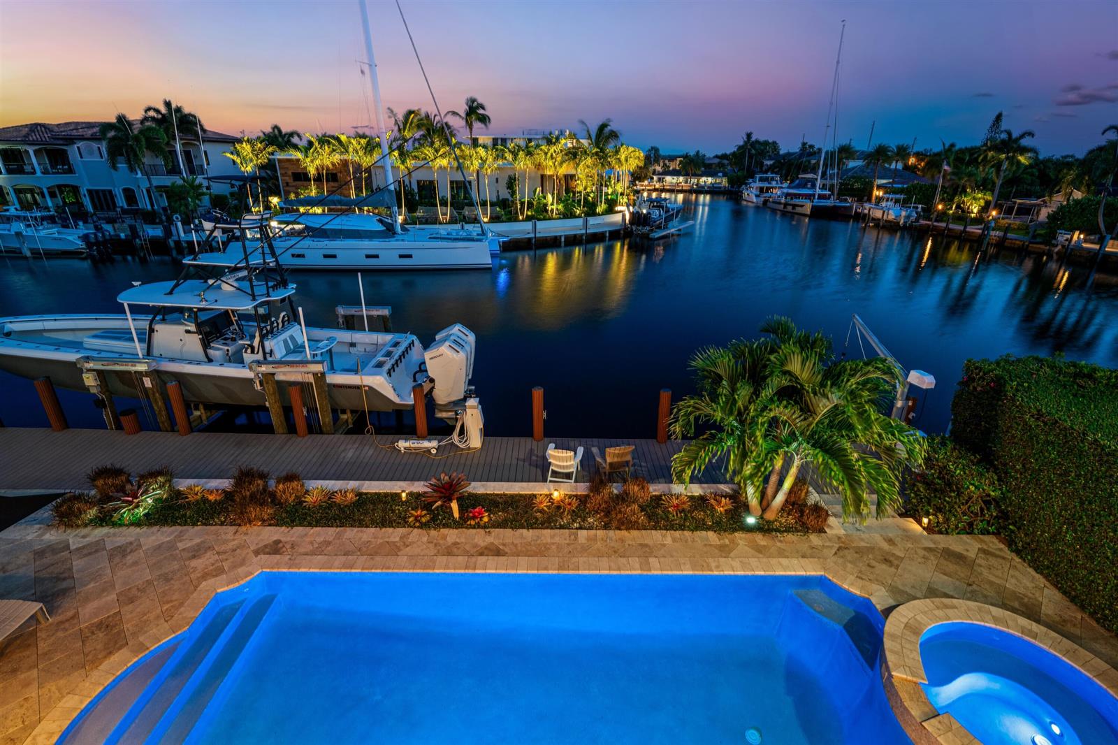 An elevated view of a swimming pool, dock, and boats on a canal at dusk — 2320 NE 34th Court, Lighthouse Point FL 33064, LIGHTHOUSE POINT, FL