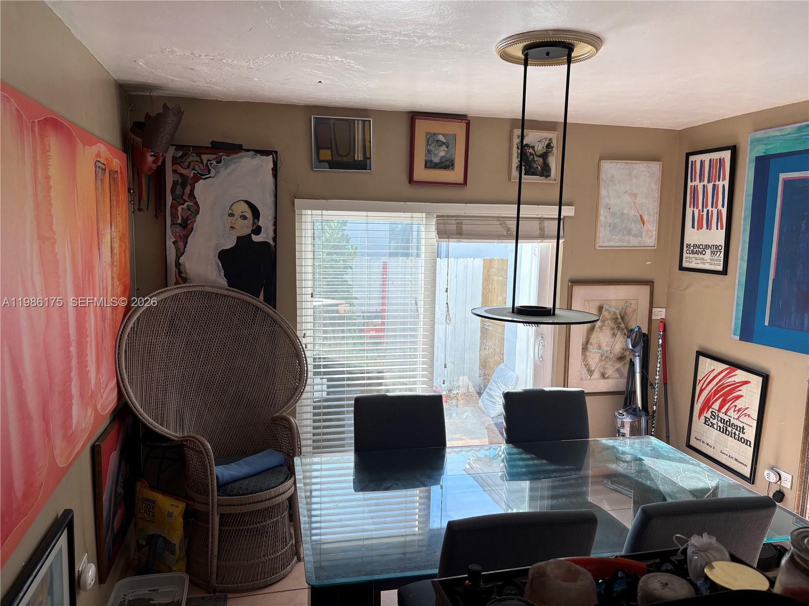 A dining room features a glass table, gray chairs, a wicker peacock chair, and wall art — 1758 SW 18th St, Miami FL 33145, MIAMI, FL
