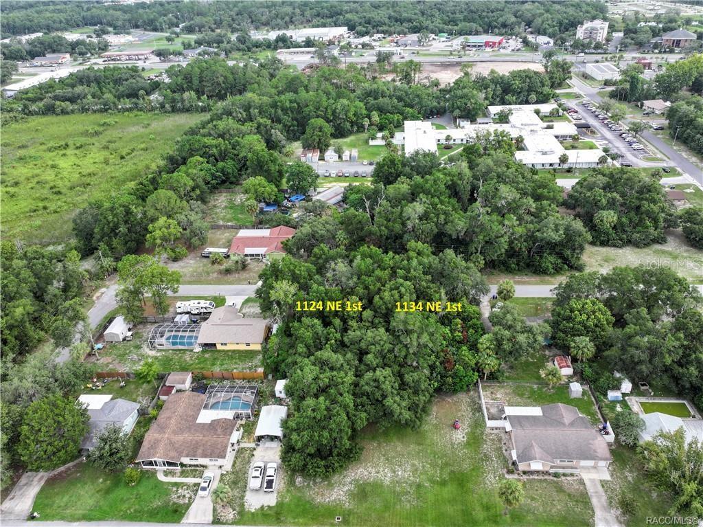An aerial view shows two adjacent wooded lots situated between residential houses and a parking lot — 1134 NE 1ST TERRACE, CRYSTAL RIVER, FL