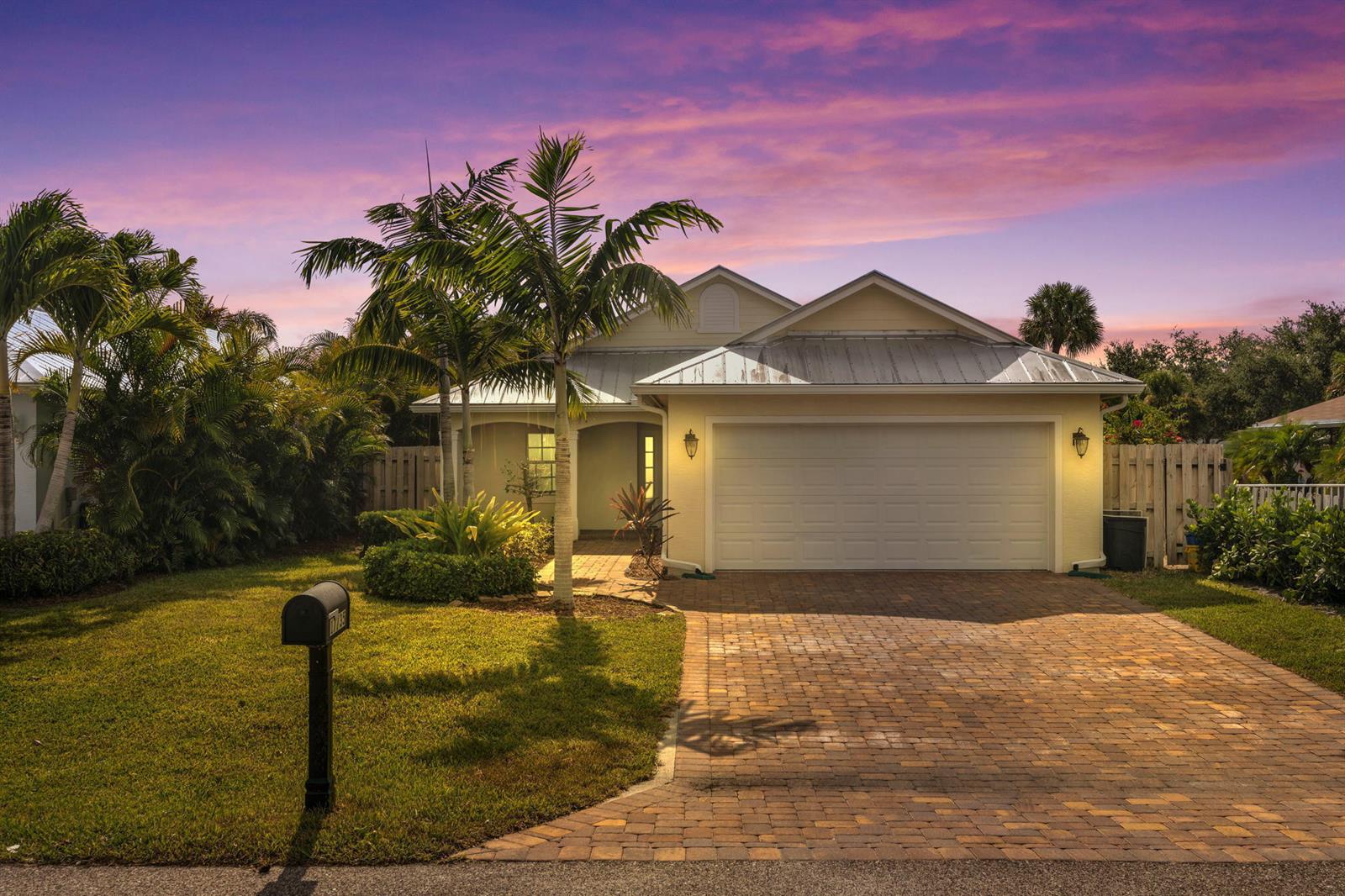 A single-story house with a metal roof, a brick driveway, and palm trees at sunset — 17735 CARVER Avenue, Jupiter FL 33458, JUPITER, FL