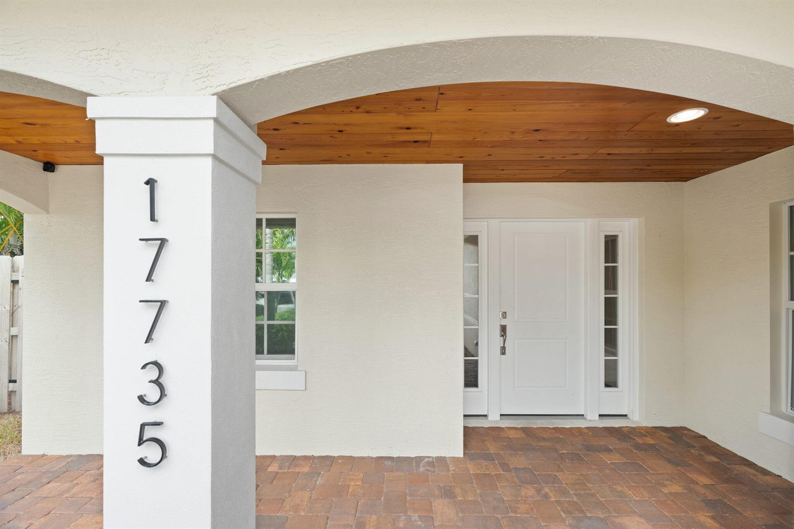A covered entryway features a white pillar with house numbers, a wood-paneled ceiling, and pavers — 17735 CARVER Avenue, Jupiter FL 33458, JUPITER, FL