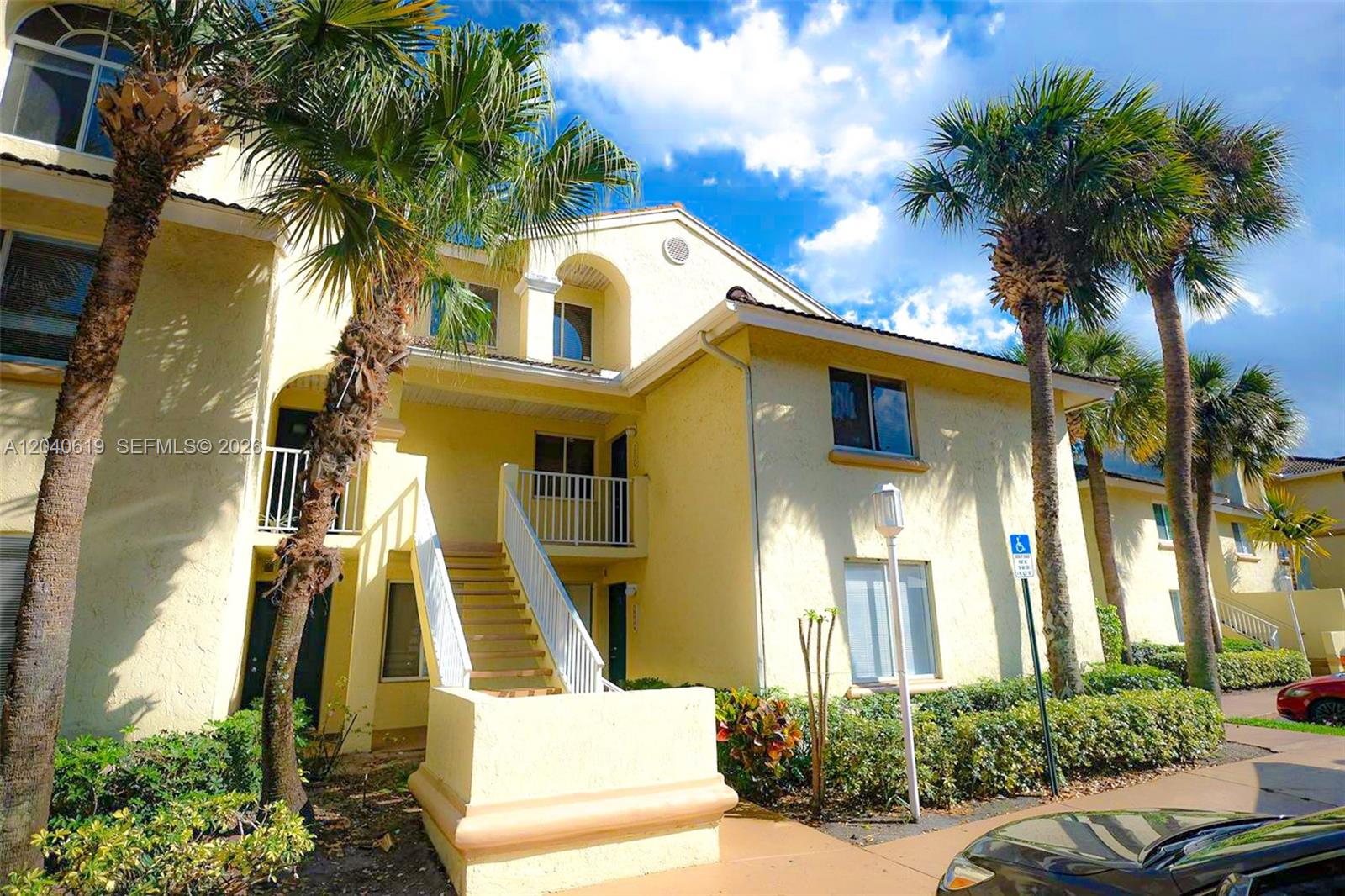 A two-story yellow stucco apartment building features an exterior staircase and surrounding palm trees — 3204 Glenmoor Dr # 3204, West Palm Beach FL 33409, WEST PALM BEACH, FL