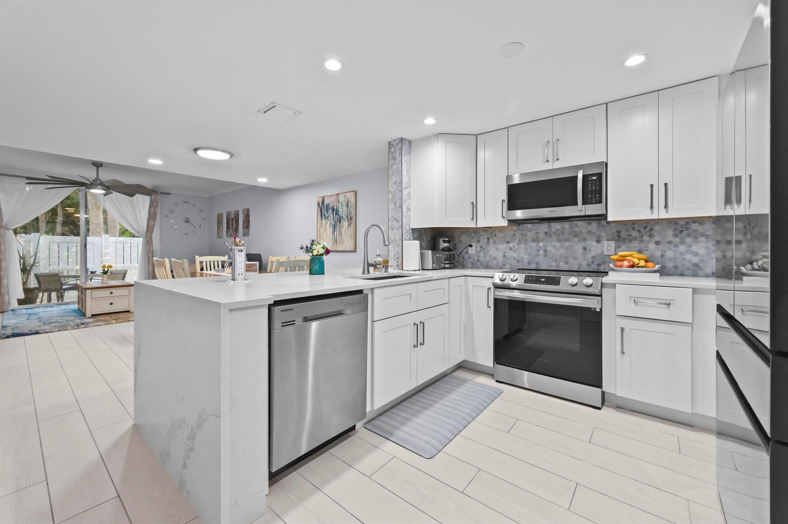 A modern kitchen features white cabinets, stainless steel appliances, and a quartz-topped island — 866 E Jeffery Street, Boca Raton FL 33487, BOCA RATON, FL