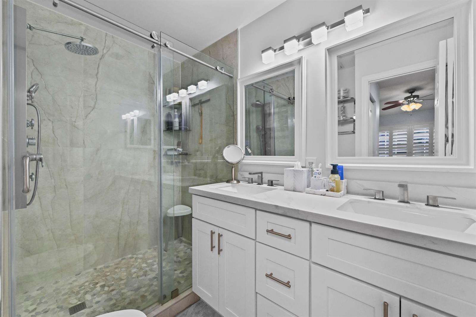 A modern bathroom features a double vanity, white cabinetry, and a glass-enclosed walk-in shower — 866 E Jeffery Street, Boca Raton FL 33487, BOCA RATON, FL
