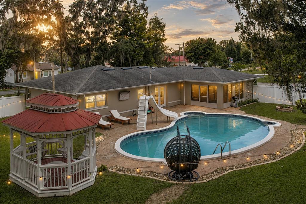 An exterior view of a house with a backyard pool, slide, and white gazebo — 14320 13TH STREET, DADE CITY, FL