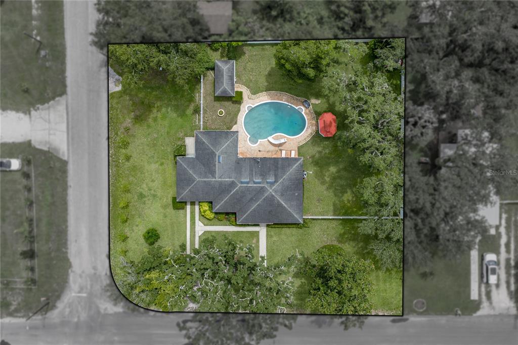 This aerial view shows a house with a pool, patio, and yard on a lot — 14320 13TH STREET, DADE CITY, FL