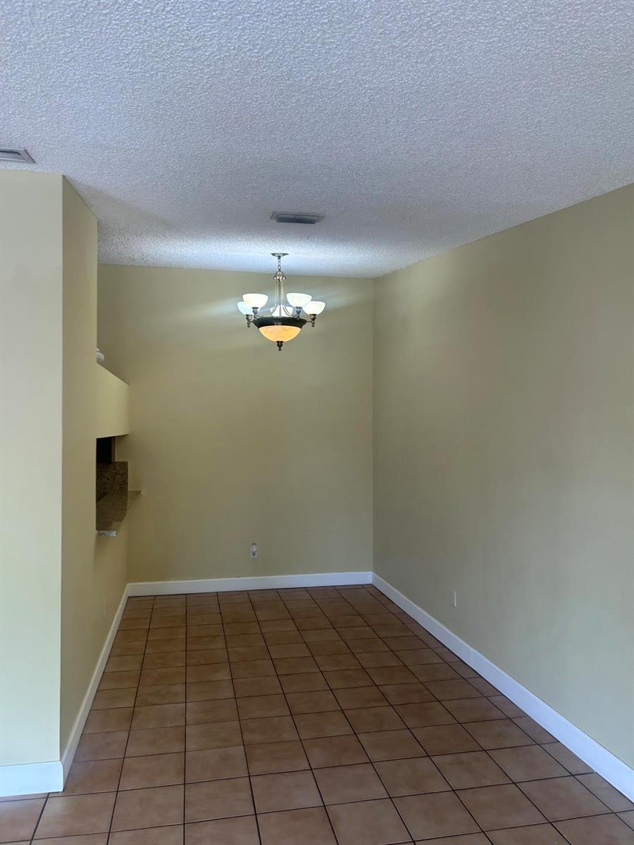 A dining area features tan walls, a tile floor, and a hanging chandelier — 18310 Mediterranean Boulevard # 24, Hialeah FL 33015, HIALEAH, FL