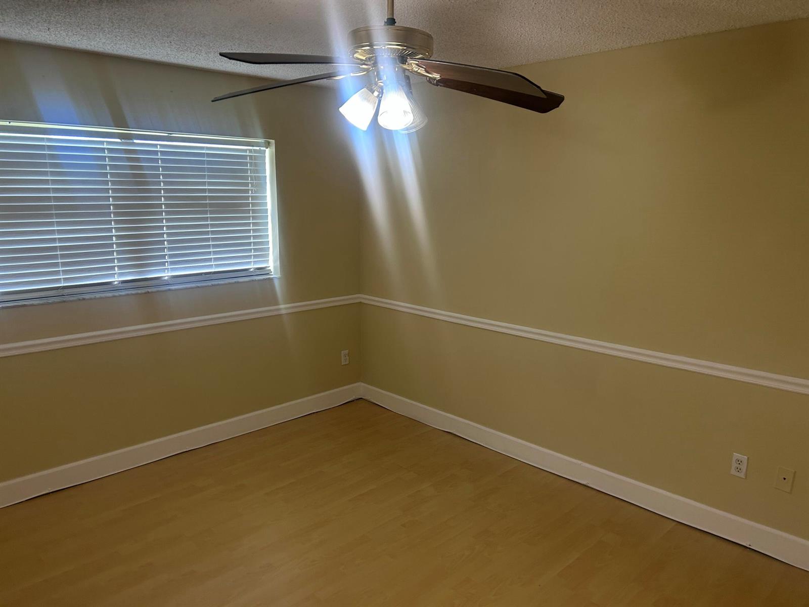 An empty room features light-colored walls with chair rail molding, wood-look flooring, and a ceiling fan — 18310 Mediterranean Boulevard # 24, Hialeah FL 33015, HIALEAH, FL