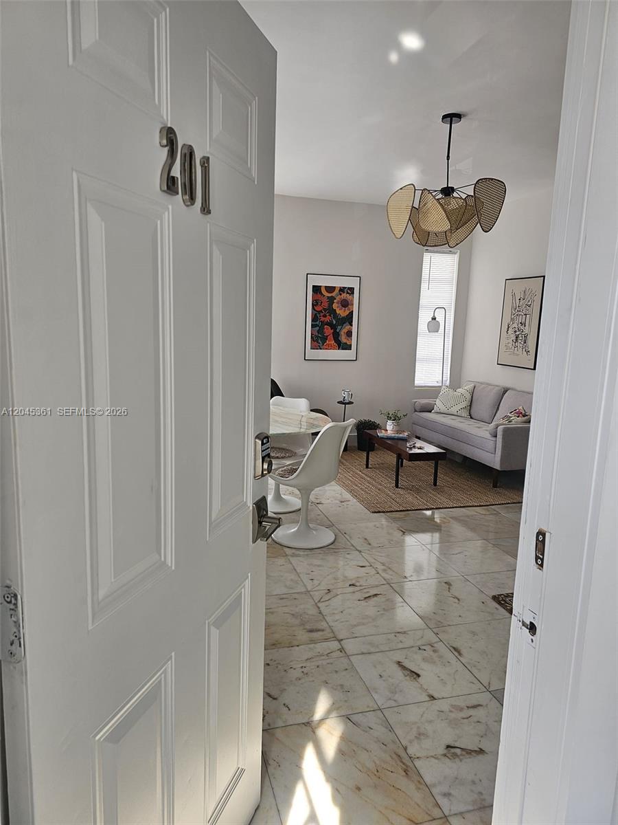 A view through an open door reveals a living room with marble floors and furniture — 801 8th St # 201, Miami Beach FL 33139, MIAMI BEACH, FL