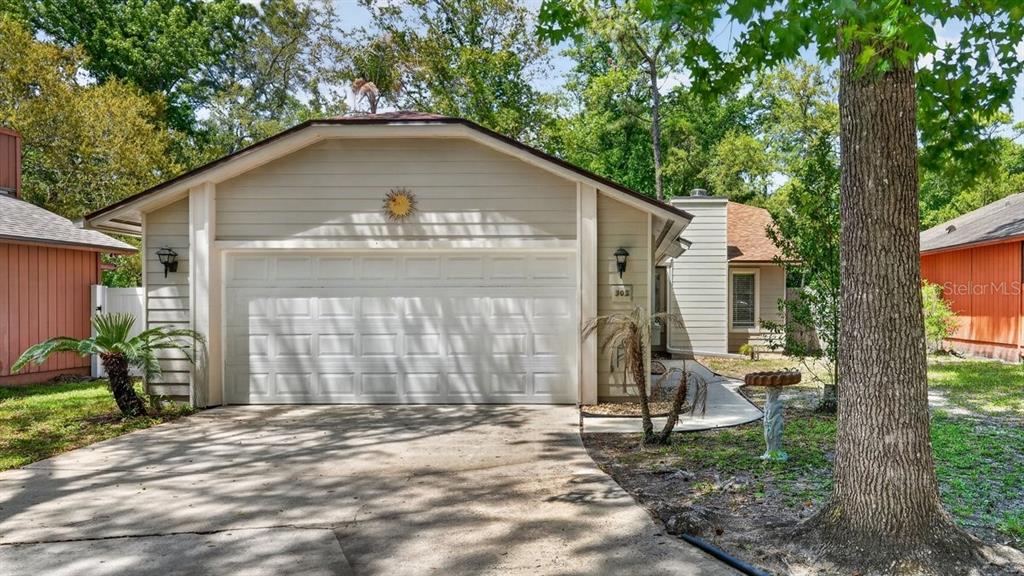 A single-story house with a beige exterior, a two-car garage, and a concrete driveway — 302 GATEWOOD COURT, ORMOND BEACH, FL