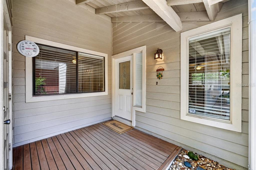 A covered wooden porch features a front door, two windows, and a wall-mounted thermometer — 302 GATEWOOD COURT, ORMOND BEACH, FL