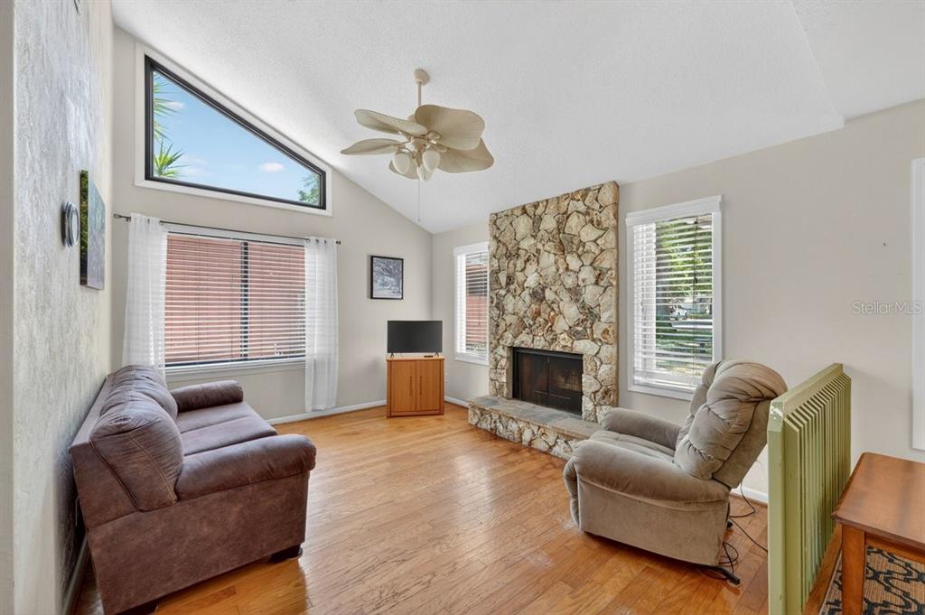 A living room features a stone fireplace, hardwood floors, a vaulted ceiling, and a recliner — 302 GATEWOOD COURT, ORMOND BEACH, FL