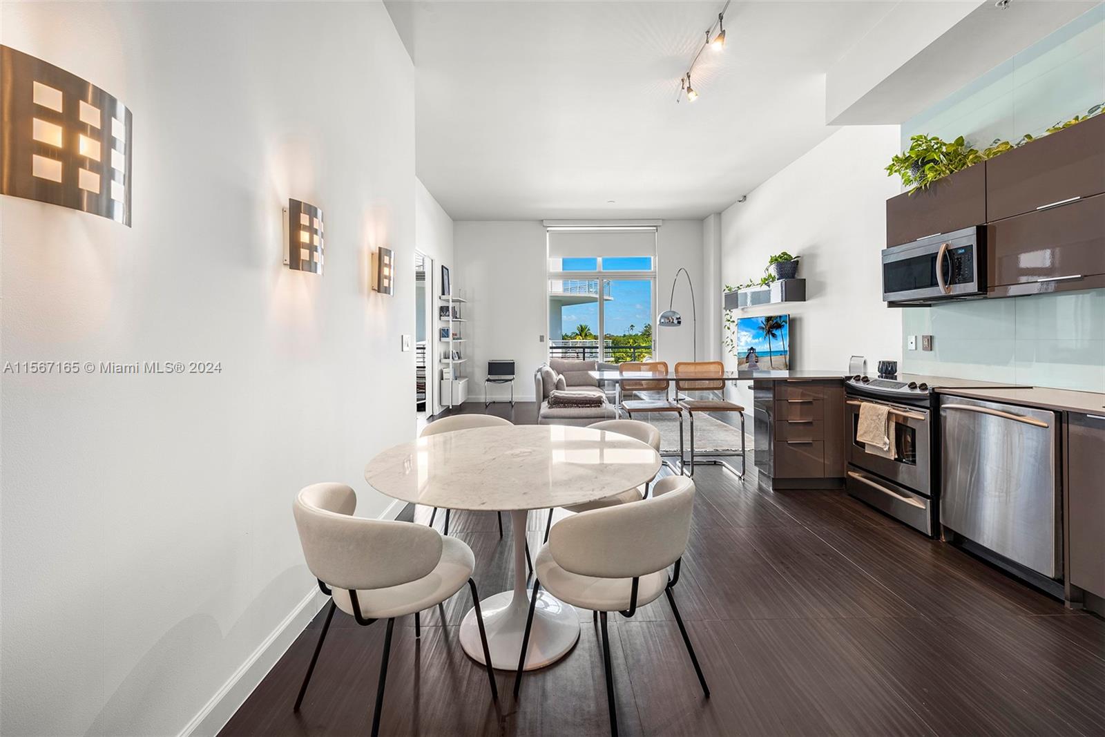 This open-concept living area features a round dining table, modern kitchen, and balcony view — 2001 Meridian Ave # 517, Miami Beach FL 33139, MIAMI BEACH, FL