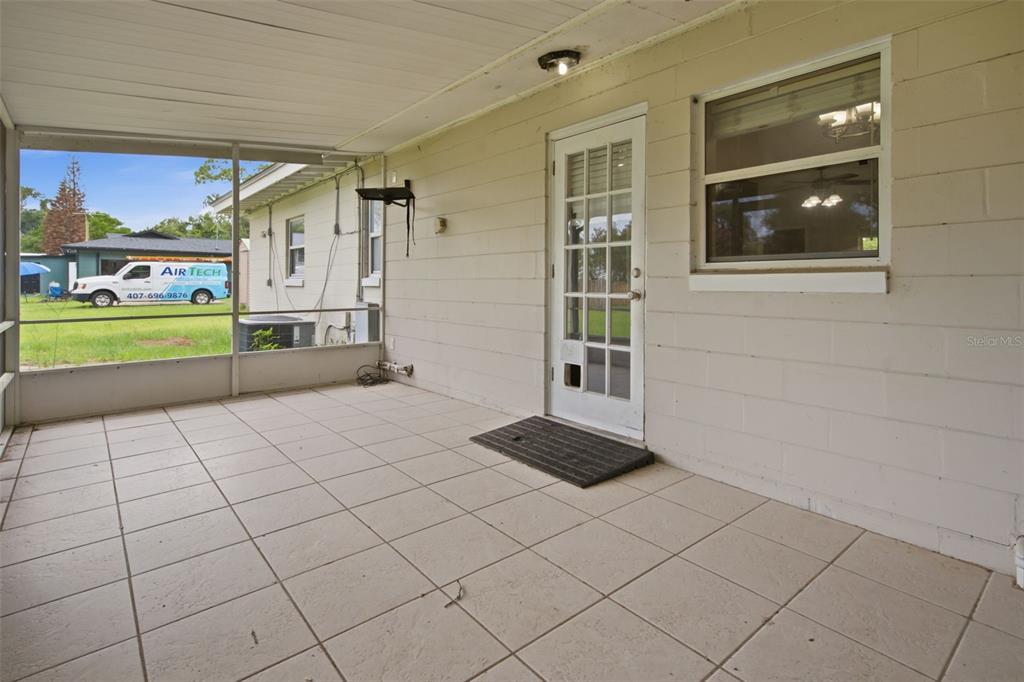 A screened-in patio with tiled flooring, a white door, and a window — 452 OAKHURST STREET, ALTAMONTE SPRINGS, FL