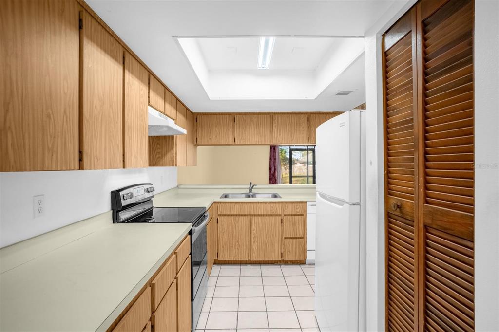 A kitchen with light wood cabinets, white countertops, a white refrigerator, and a skylight — 1822 FOXHALL CIRCLE UNIT 1822, KISSIMMEE, FL