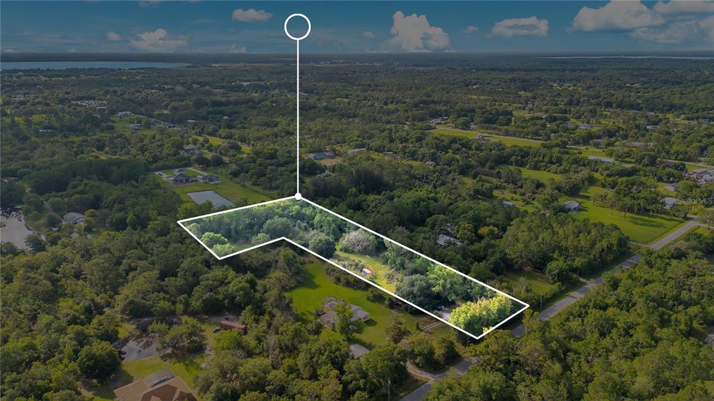 An aerial view shows a wooded residential lot outlined in white against a rural landscape — 0 HENRY J AVENUE, ST CLOUD, FL