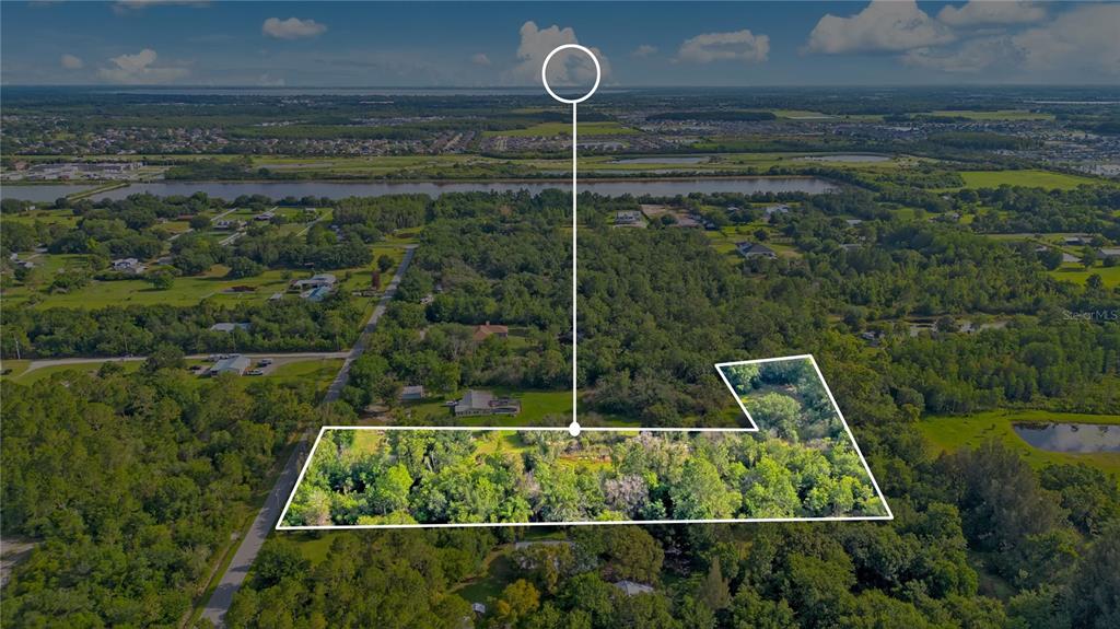 An aerial view shows a wooded, L-shaped plot of land outlined in white — 0 HENRY J AVENUE, ST CLOUD, FL