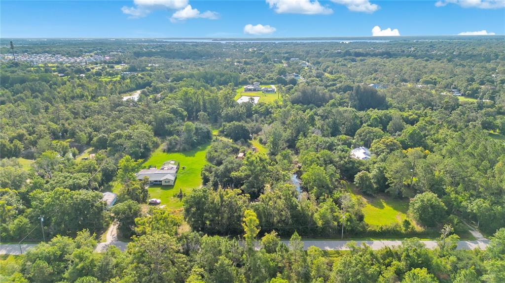 An aerial view shows a rural property with houses, green lawns, and dense surrounding trees — 0 HENRY J AVENUE, ST CLOUD, FL