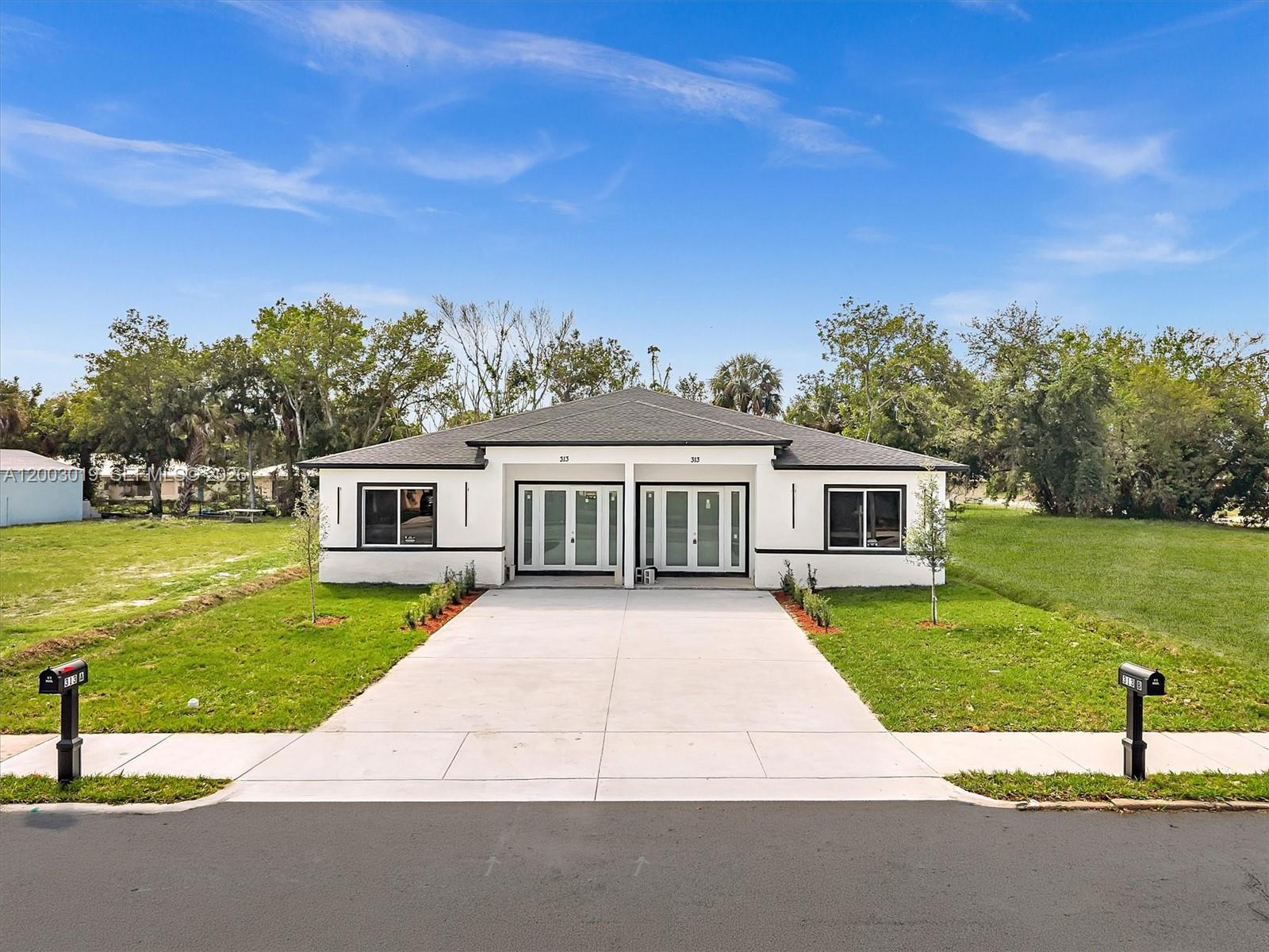 A modern, white duplex with a shared concrete driveway and two front entrances — 313 S 13th St, Fort Pierce FL 34950, FORT PIERCE, FL