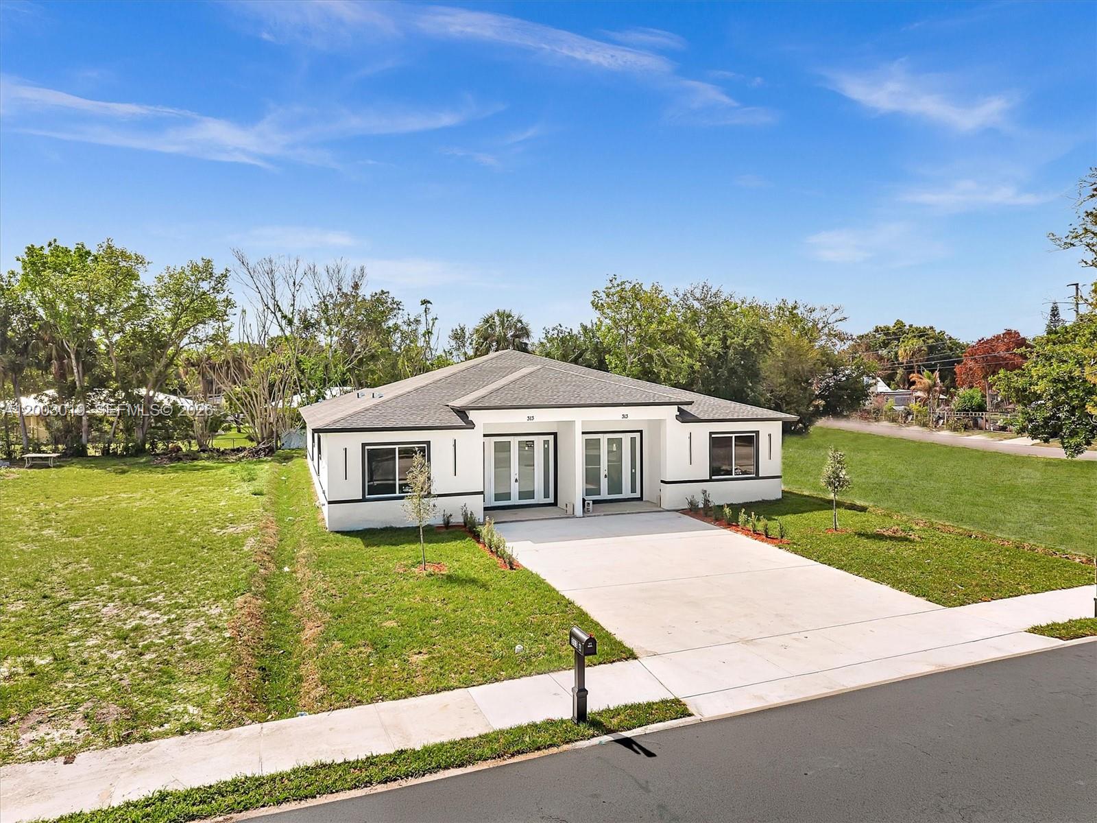 A single-story duplex with a white exterior, dark trim, and a concrete driveway — 313 S 13th St, Fort Pierce FL 34950, FORT PIERCE, FL