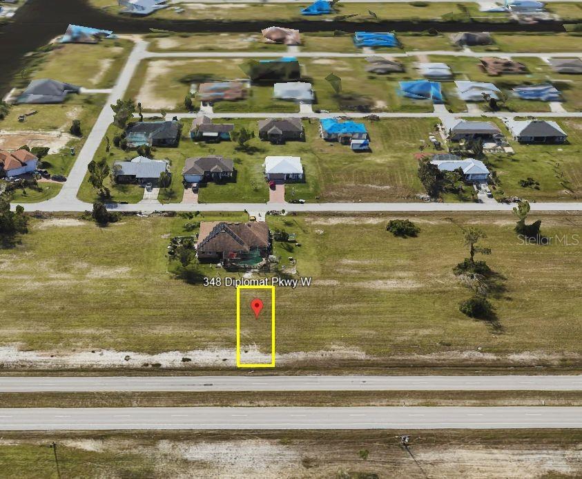 This is an aerial view of a vacant residential lot outlined in yellow — 348 DIPLOMAT PARKWAY W, CAPE CORAL, FL