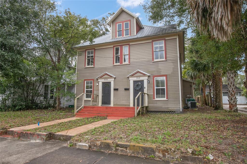 A two-story duplex with gray siding, red trim, and two front entrances with red steps — 206 W WISCONSIN AVENUE, DELAND, FL