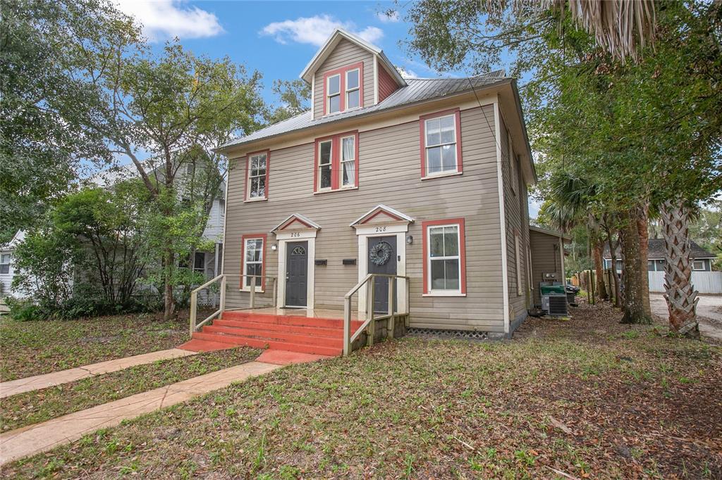 A two-story duplex with tan siding, red trim, and two front entrances with red steps — 206 W WISCONSIN AVENUE, DELAND, FL