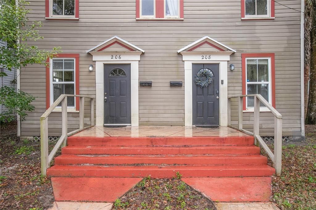 A duplex exterior features two dark front doors with pediments above red concrete steps — 206 W WISCONSIN AVENUE, DELAND, FL
