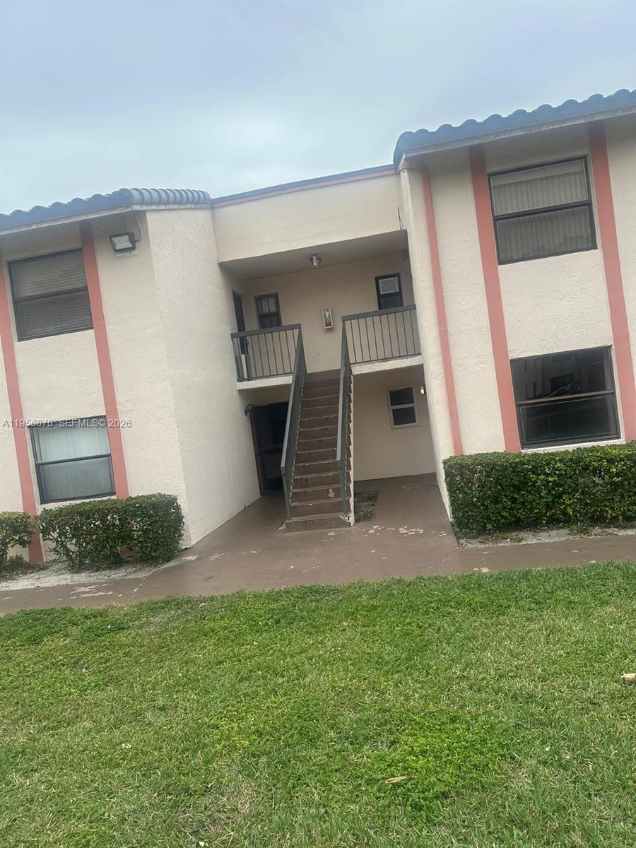 A two-story apartment building exterior features a central staircase leading to an upper balcony — 855 NE 209th St # 34, Miami FL 33179, MIAMI, FL